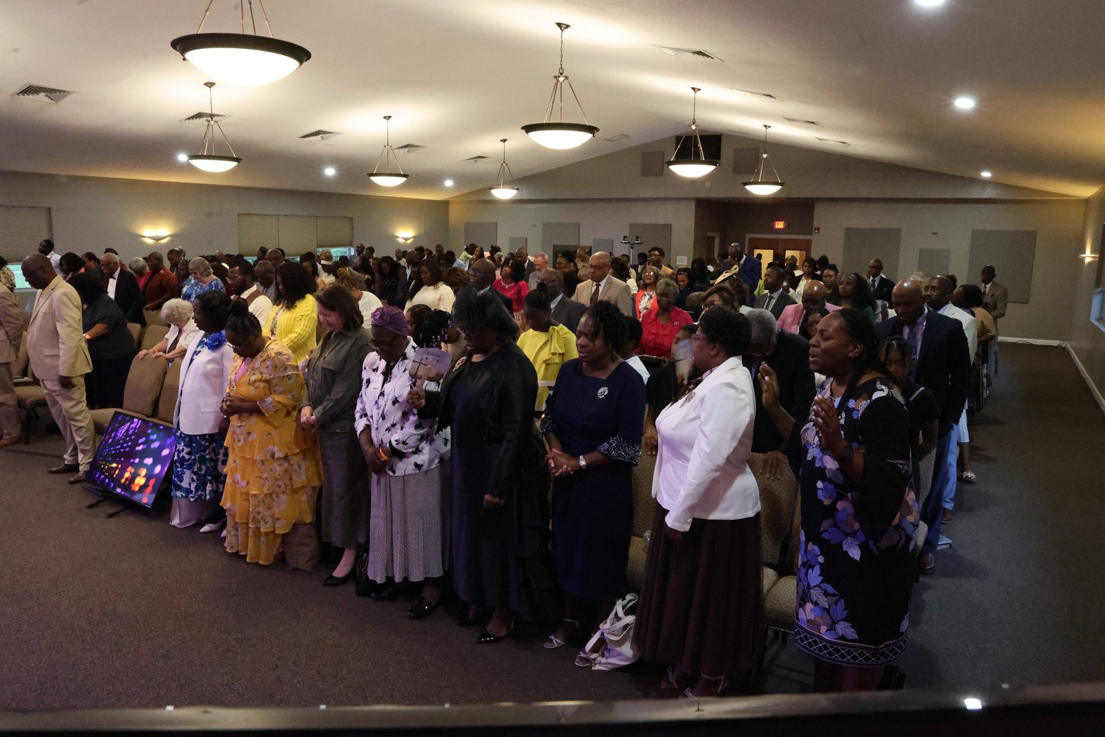 The congregation standing in prayer during a Camp Meeting service